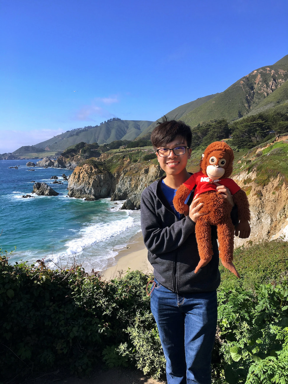 Henry Lim holding a orangutan soft toy at Big Sur, California.